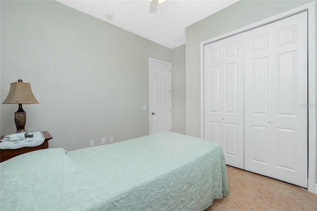 tiled bedroom with ceiling fan and a closet