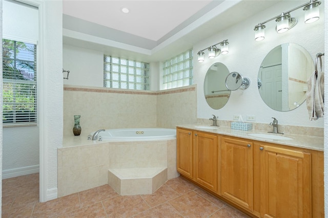 bathroom featuring tile patterned flooring, vanity, and a relaxing tiled tub