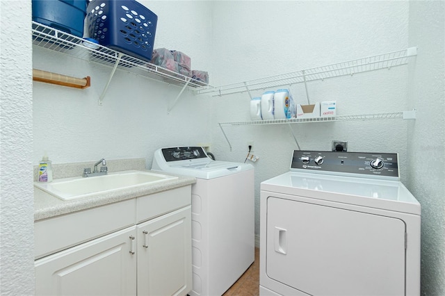 clothes washing area featuring cabinets, sink, and washing machine and clothes dryer