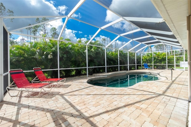 view of pool with glass enclosure and a patio area