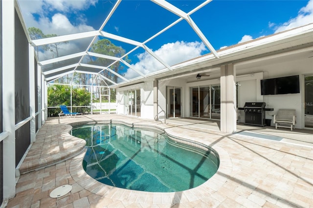 view of swimming pool featuring ceiling fan, area for grilling, a lanai, and a patio area