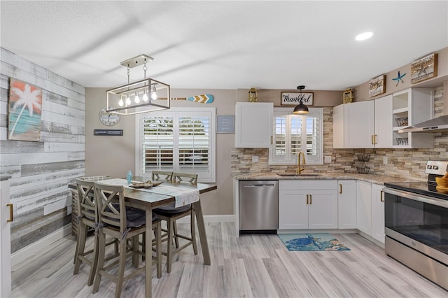 kitchen with stainless steel appliances, hanging light fixtures, white cabinetry, and sink