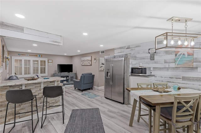 kitchen featuring a breakfast bar, light wood-type flooring, and appliances with stainless steel finishes