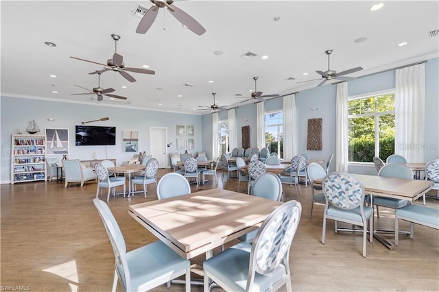 dining space with ornamental molding and light hardwood / wood-style floors