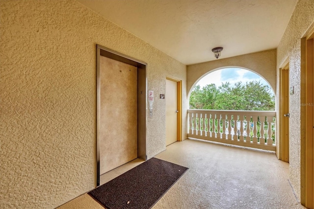 view of exterior entry with a balcony and elevator