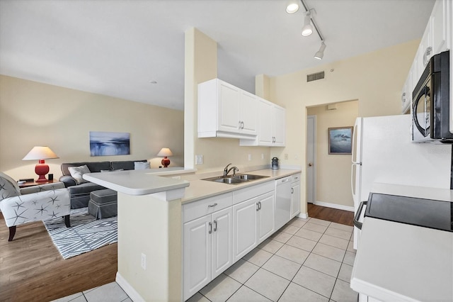 kitchen featuring sink, white cabinets, white appliances, light tile patterned floors, and kitchen peninsula