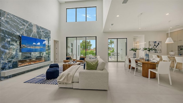 tiled living room featuring a premium fireplace and a high ceiling