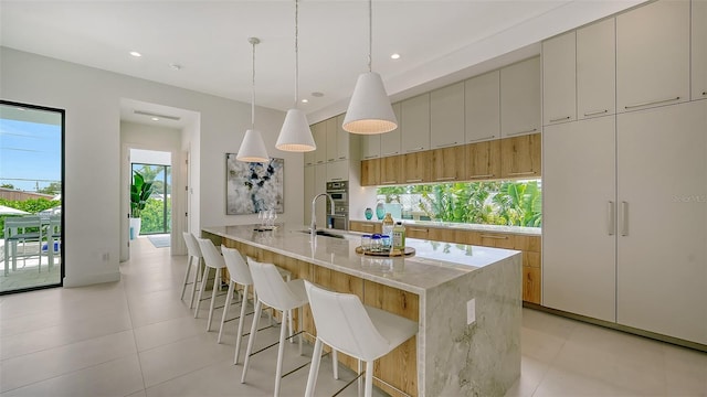 kitchen with light stone countertops, kitchen peninsula, stainless steel double oven, light tile patterned floors, and hanging light fixtures