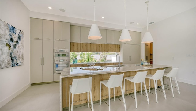 kitchen featuring cream cabinets, a spacious island, sink, double oven, and decorative light fixtures