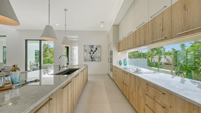 kitchen with light stone countertops, sink, decorative light fixtures, black electric cooktop, and white cabinets