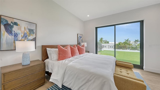 bedroom featuring access to exterior, light hardwood / wood-style floors, and lofted ceiling