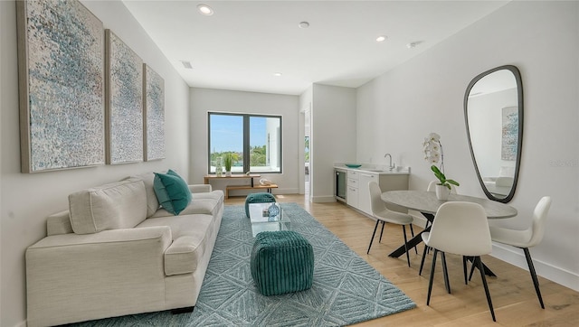 living room with light wood-type flooring, sink, and beverage cooler