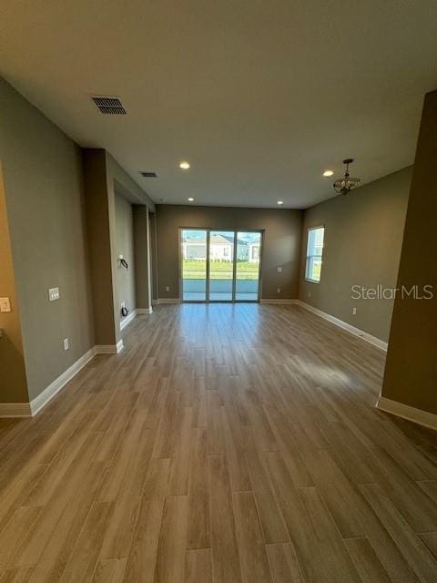 unfurnished living room featuring light wood-type flooring and a notable chandelier