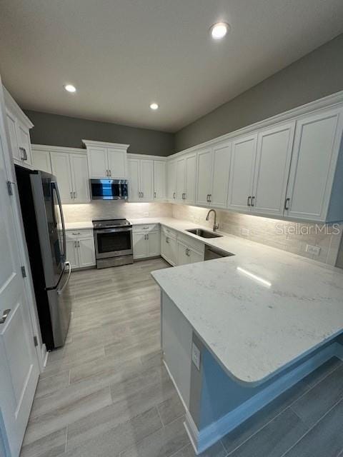 kitchen featuring white cabinets, kitchen peninsula, and stainless steel appliances