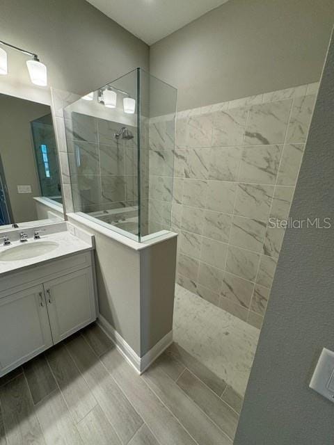 bathroom with tiled shower and vanity