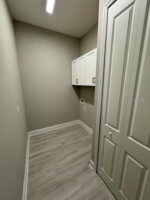 laundry room with cabinets, light hardwood / wood-style floors, and hookup for an electric dryer