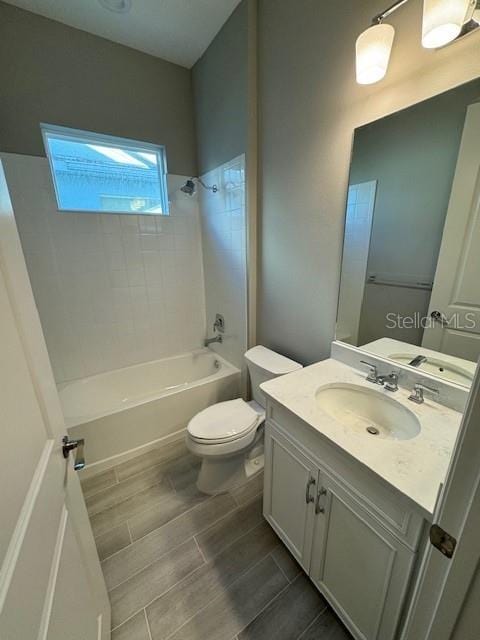 full bathroom with tiled shower / bath, toilet, and vanity