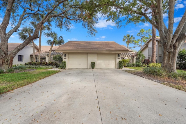 view of front of house with a detached garage, a tiled roof, a front lawn, and stucco siding