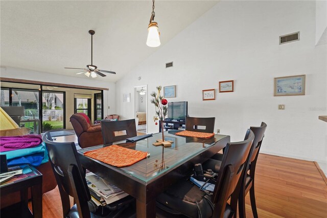 dining room with ceiling fan, light hardwood / wood-style flooring, and high vaulted ceiling