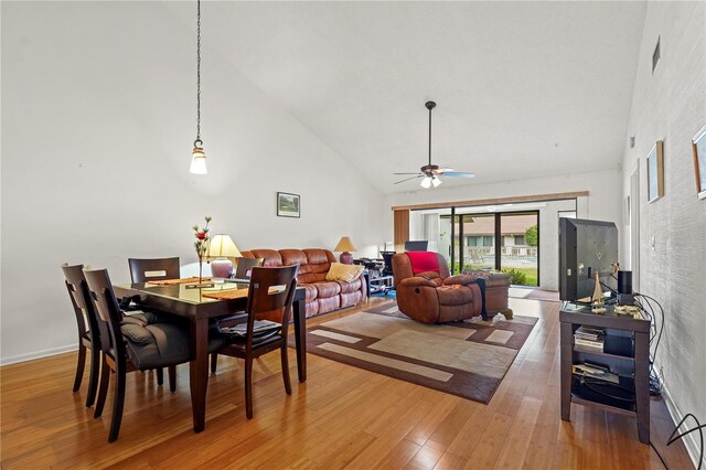 dining space featuring ceiling fan, wood-type flooring, and high vaulted ceiling