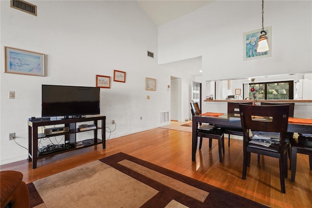 dining space featuring hardwood / wood-style floors and high vaulted ceiling