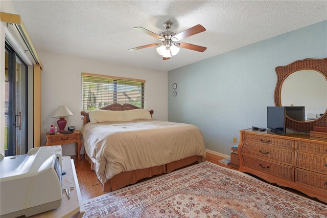 bedroom with hardwood / wood-style floors, ceiling fan, and a textured ceiling