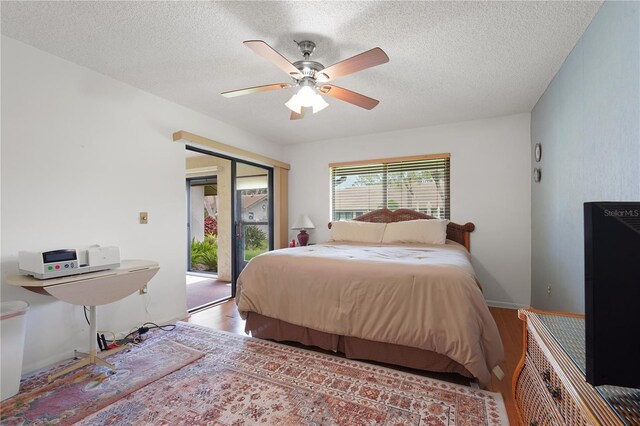 bedroom featuring hardwood / wood-style flooring, ceiling fan, access to exterior, and a textured ceiling