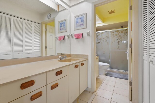 bathroom featuring toilet, vanity, tile patterned floors, and a shower with shower door