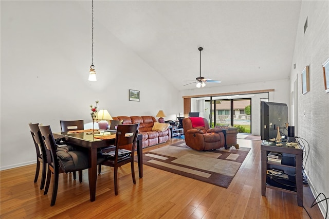 dining space featuring high vaulted ceiling, a ceiling fan, visible vents, and wood finished floors