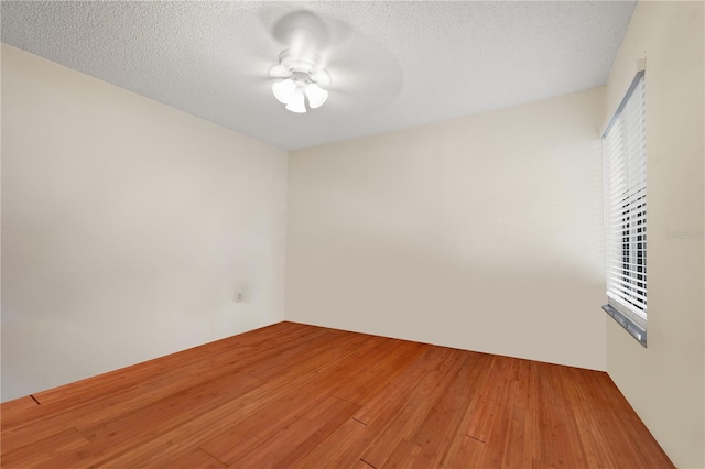 unfurnished room with a textured ceiling, a ceiling fan, and wood finished floors