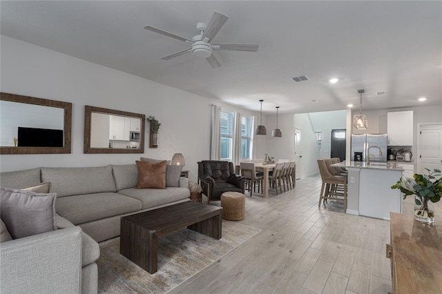 living room with ceiling fan and light hardwood / wood-style flooring