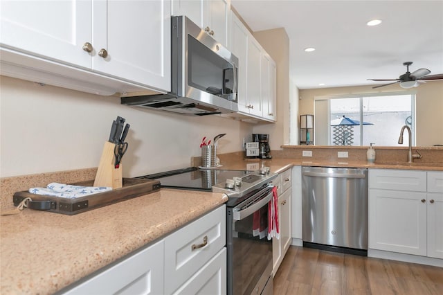 kitchen with appliances with stainless steel finishes, ceiling fan, dark wood-type flooring, sink, and white cabinetry