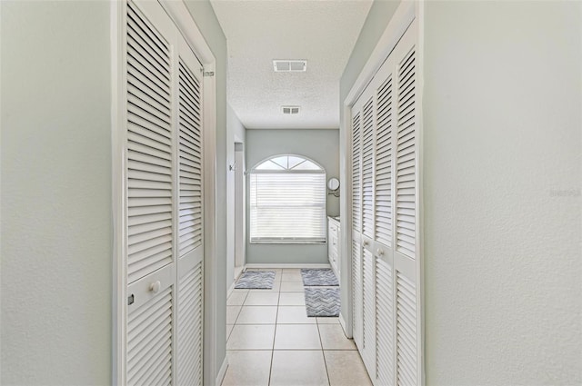 hallway featuring a textured ceiling and light tile patterned flooring