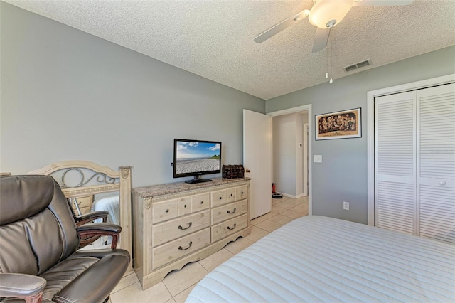 tiled bedroom with a textured ceiling, ceiling fan, and a closet