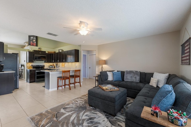 living room with a textured ceiling, ceiling fan, and light tile patterned floors