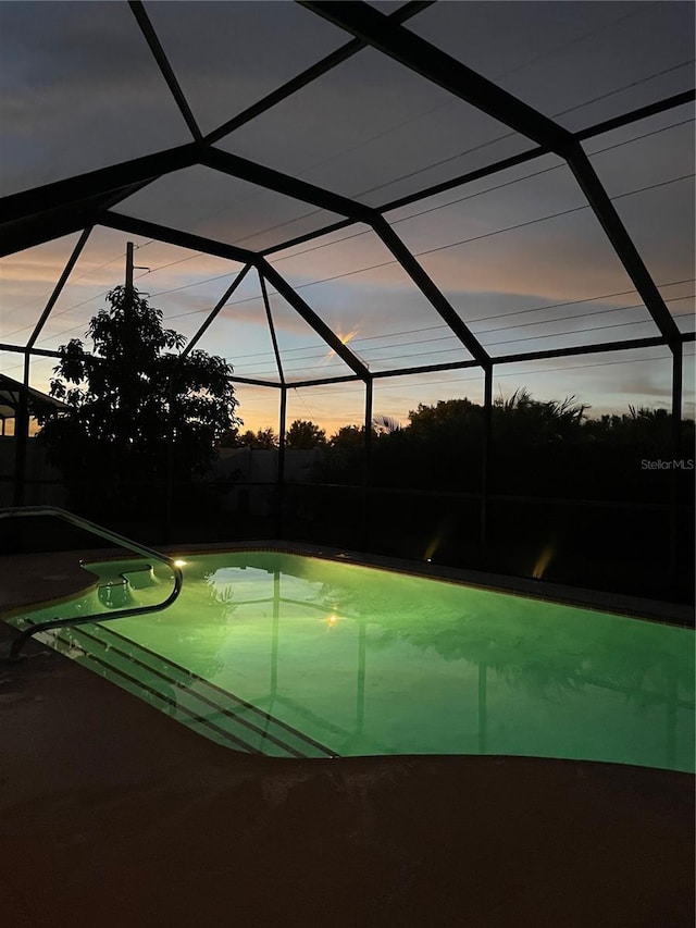 pool at dusk featuring glass enclosure