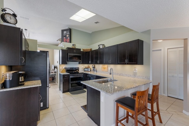 4135 Dover Dr E, Bradenton, FL 34203 - kitchen featuring a sink, stainless steel appliances, a peninsula, light tile patterned floors, and a breakfast bar area