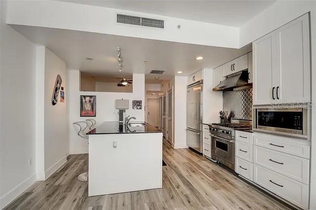 kitchen with white cabinetry, appliances with stainless steel finishes, ceiling fan, and light hardwood / wood-style flooring