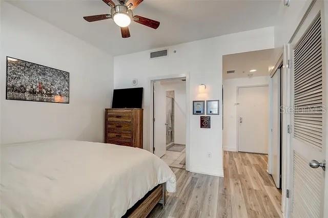 bedroom featuring light wood-type flooring, ceiling fan, and ensuite bathroom