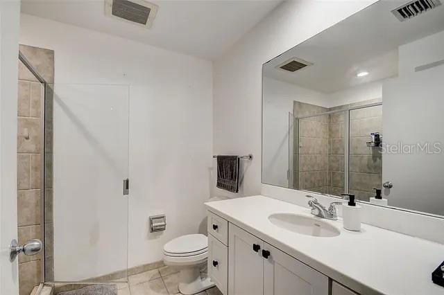 bathroom featuring a shower with door, vanity, and toilet