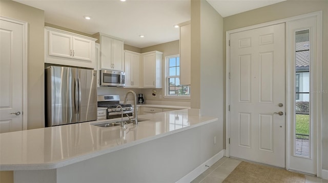 kitchen featuring stainless steel appliances, white cabinetry, light tile patterned floors, sink, and kitchen peninsula