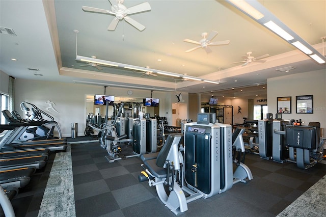 gym featuring ceiling fan and a tray ceiling