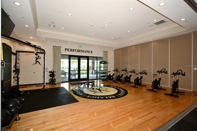 exercise room featuring a tray ceiling, french doors, and light hardwood / wood-style floors