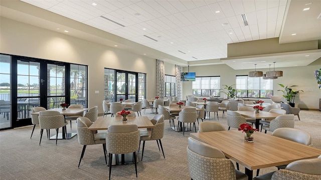 dining area with a high ceiling and light colored carpet