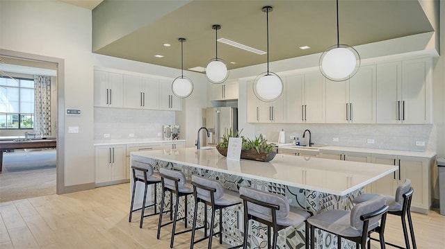 5431 Taliaferro Ct, Palmetto, FL 34221 - kitchen featuring high end refrigerator, a kitchen bar, backsplash, light wood finished floors, and an island with sink