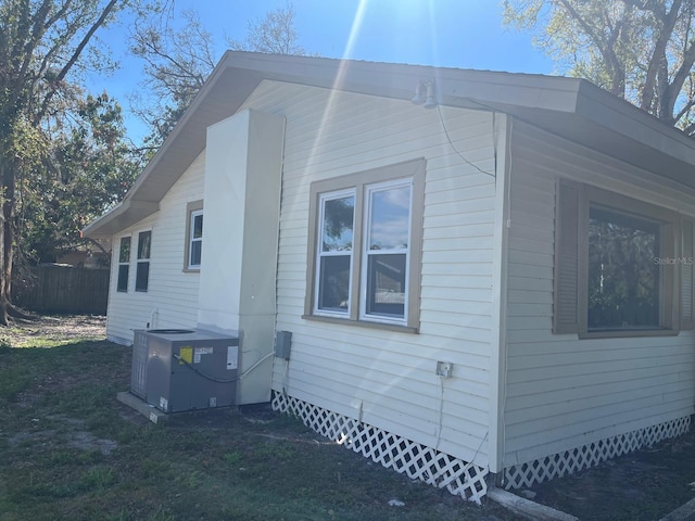 view of property exterior with a lawn, fence, and cooling unit