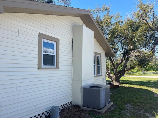 view of side of home featuring cooling unit and a lawn