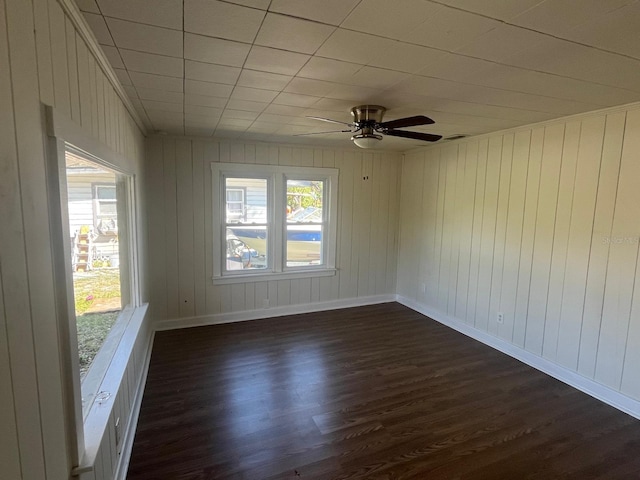 empty room with ceiling fan, dark wood-type flooring, a wealth of natural light, and baseboards