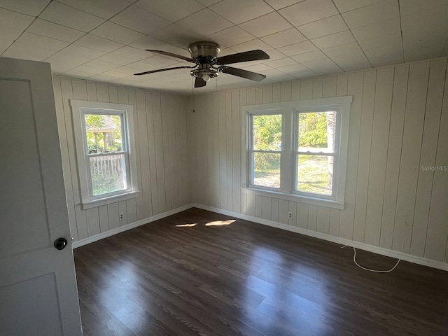 spare room with ceiling fan, baseboards, and dark wood-type flooring