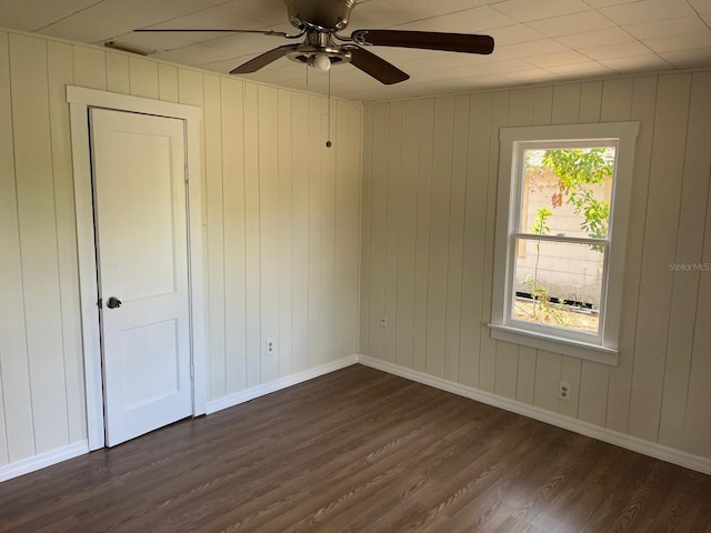 empty room with dark wood-style flooring, ceiling fan, and baseboards